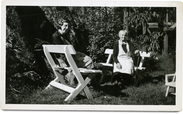 Nostalgisk foto av to damer på benker i hagen.