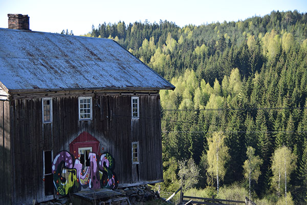 Foto av gammel tømmerbygning. Bygningen er skjendet med grafitti.